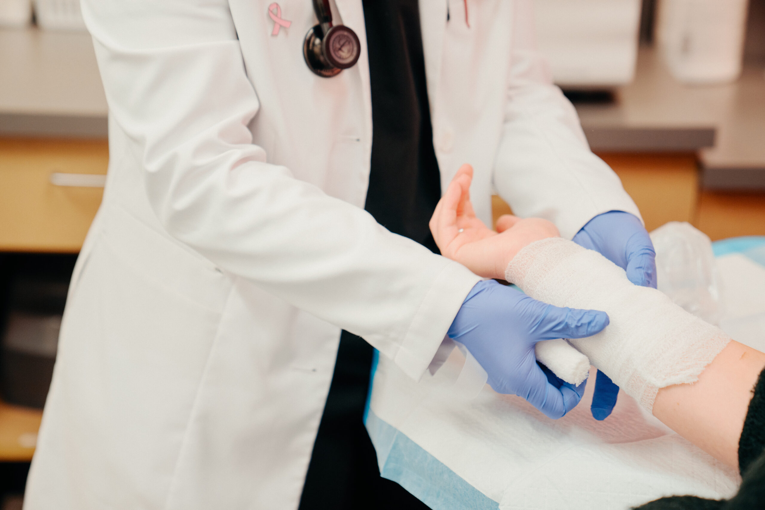 AFC healthcare provider wrapping a patient’s lower right arm in bandage after experiencing a burn or rash.